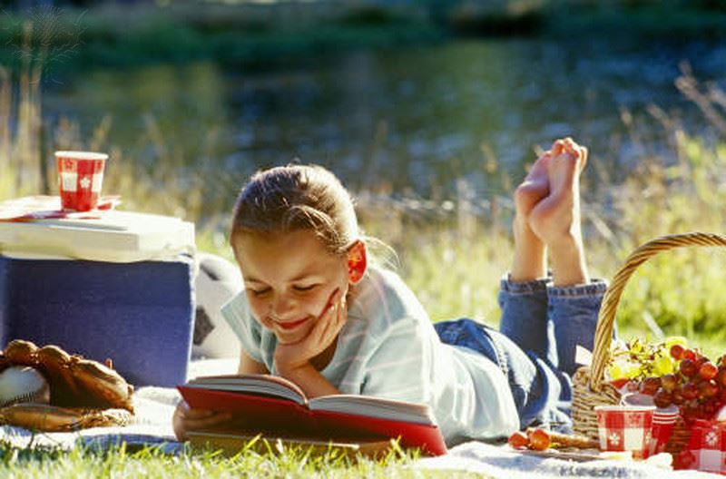 girl reading book in grass girl reading book in grass